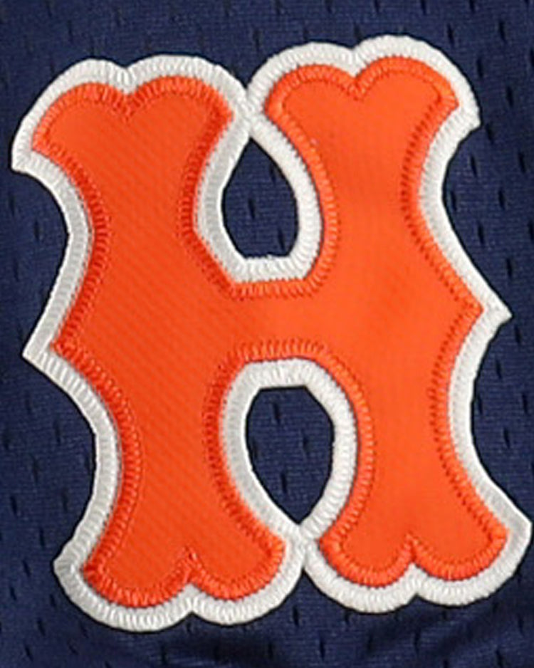 An orange, bubble-shaped H with a white outline is stitched onto dark blue mesh, echoing vintage styles on the EFF Hiroshima Carp EFF DNA Replica V-Neck Mesh Jersey.