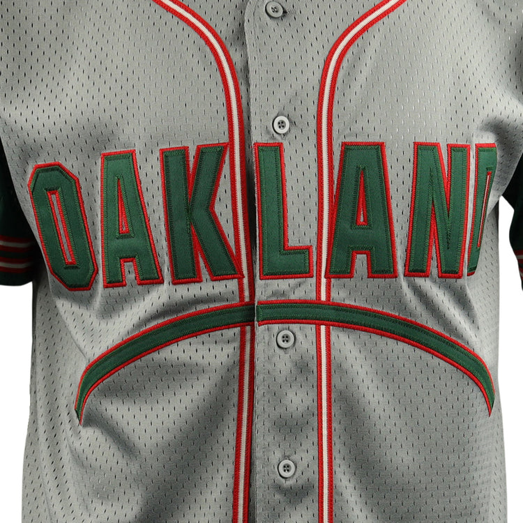 A close-up of the EFF Oakland Oaks EFF DNA Replica Button-Up Mesh Jersey shows bold green and red OAKLAND lettering, with matching trim on the buttons and collar, echoing vintage Pacific Coast League styles.