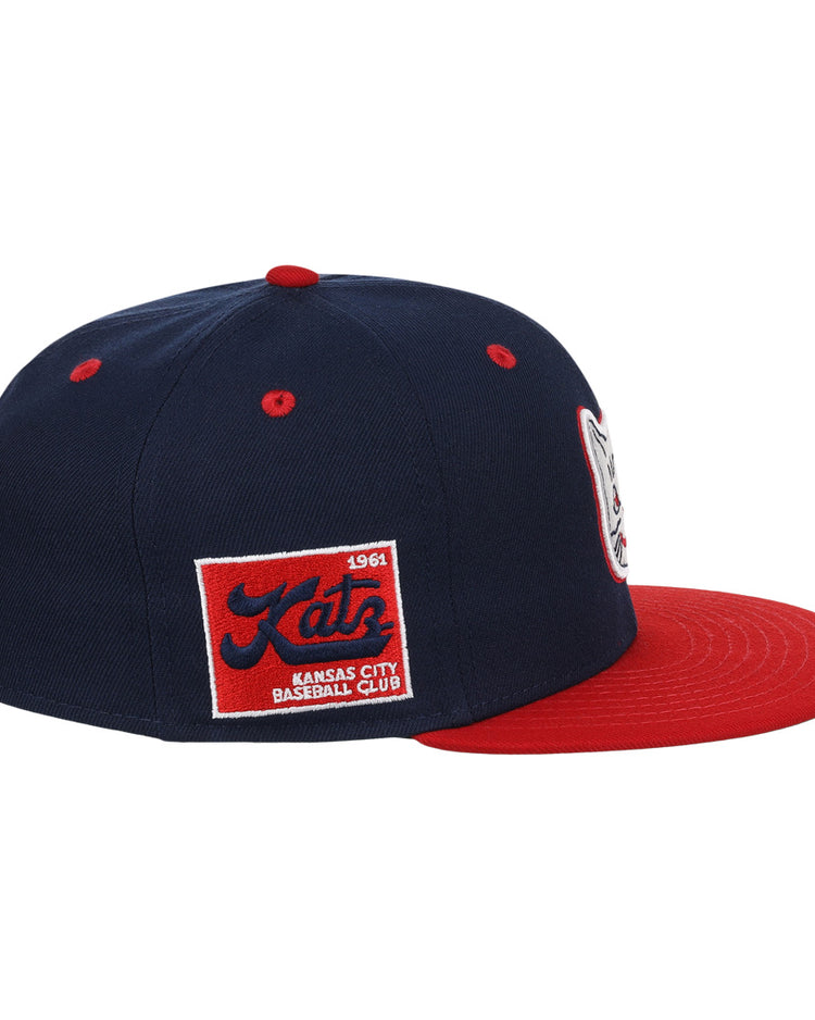 The Kansas City Katz EFF DNA Fitted Ballcap by EFF is a vintage-inspired navy cap with a red brim, featuring a Katz logo patch on the front and a 1961 Katz Kansas City Baseball Club patch on the side.