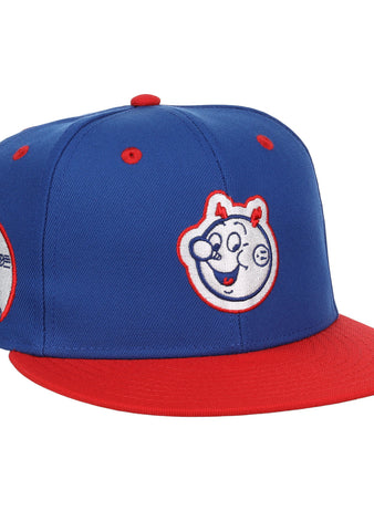 The EFF Reddy Kilowatt EFF DNA Fitted Ballcap features a blue vintage design with a red brim, cartoon bear face front, and side patch of a bear playing baseball—classic style inspired by Ebbets Field Flannels.