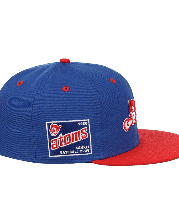 The Sankei Atoms EFF DNA Fitted Ballcap by EFF is a blue vintage-style cap with a red brim, embroidered patches, and a side patch that reads Atoms 1950 SANKEI BASEBALL CLUB with an Atom Boy mascot.