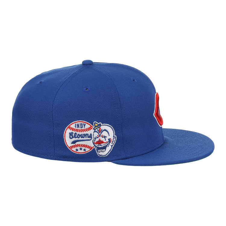 The EFF Indianapolis Clowns NLB Team Color Fitted Ballcap is a blue vintage-inspired cap with side patches—a baseball labeled INDY Browns and a smiling face with a red hat—honoring the Negro American League’s Clowns, plus a bold red C on the front.