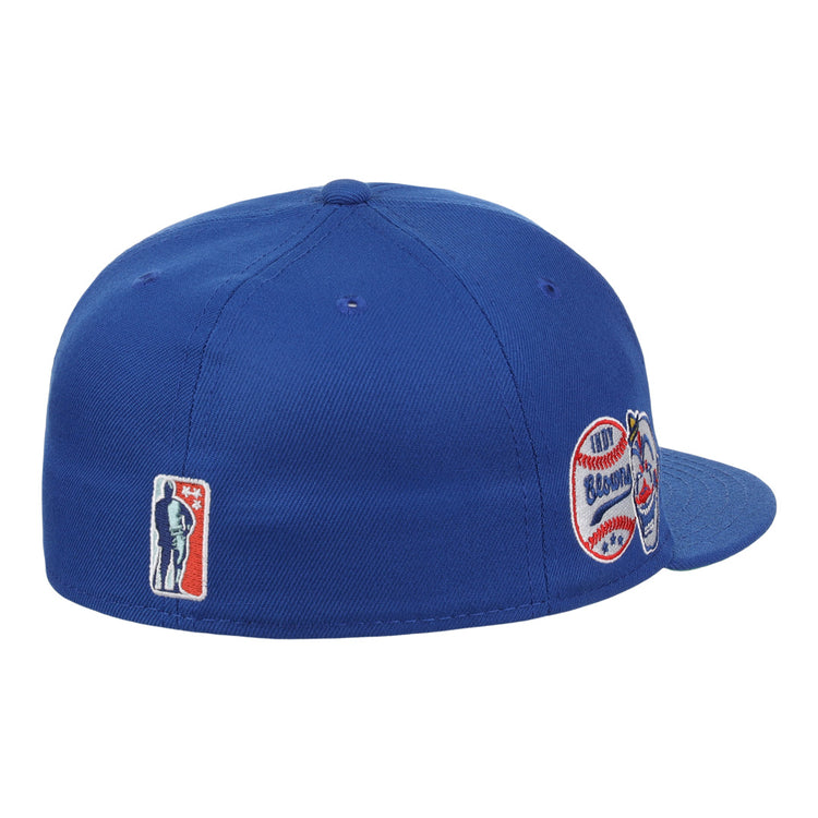 The EFF Indianapolis Clowns NLB Team Color Fitted Ballcap, shown from a rear side angle in royal blue, features vintage-inspired embroidered patches honoring the Negro American League team with both silhouette and baseball-themed logos.