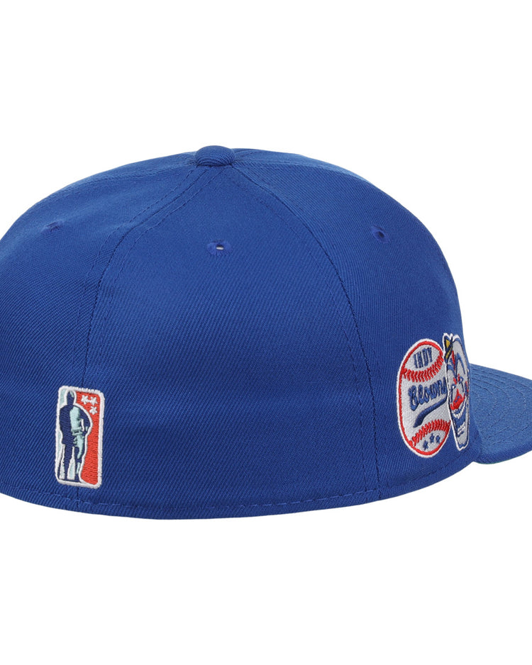 The EFF Indianapolis Clowns NLB Team Color Fitted Ballcap, shown from a rear side angle in royal blue, features vintage-inspired embroidered patches honoring the Negro American League team with both silhouette and baseball-themed logos.