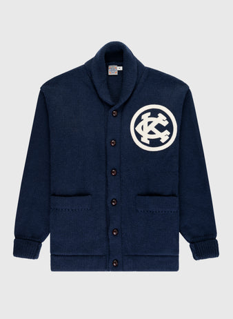The EFF Kansas City Monarchs 1922 Wool Shawl Collar Sweater is a navy blue wool cardigan with brown buttons, two front pockets, and a white KC patch on the left chest, inspired by the historic Negro Leagues World Series era.