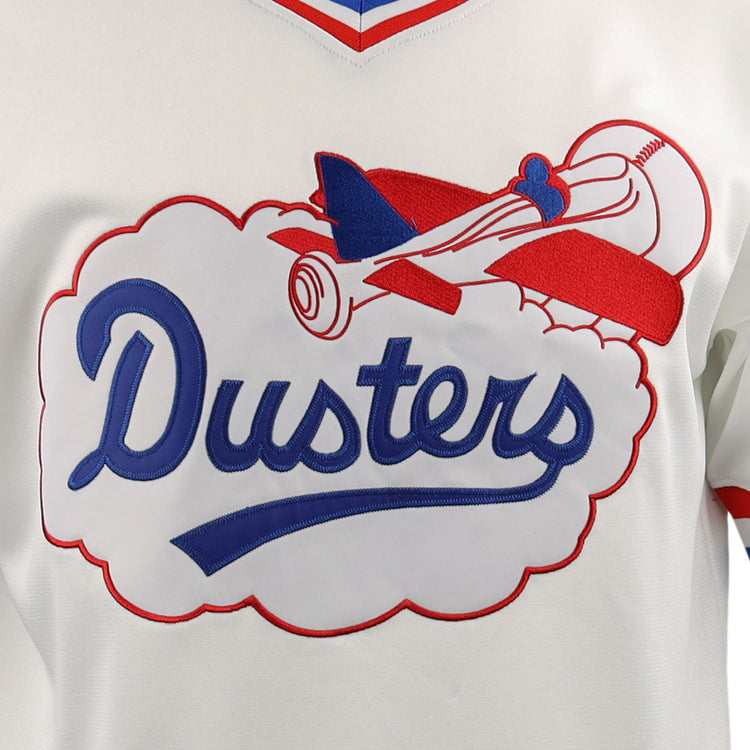 A close-up of the McAllen Dusters EFF Lone Star Baseball Jersey by EFF, showing a red and blue vintage airplane flying through a cloud with Dusters in blue script, outlined in red—design inspired by the local school district’s baseball field.