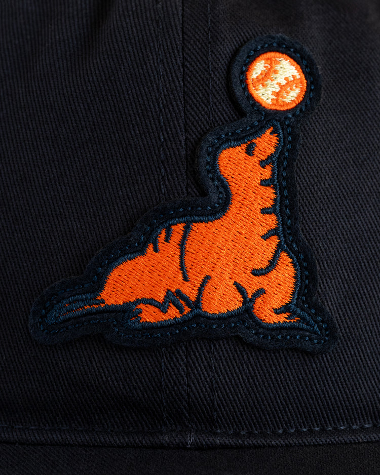 The EFF San Francisco Seals Cotton Twill Ballcap features an embroidered orange seal outlined in dark blue, balancing a ball on its nose atop black fabric—ideal for fans of vintage-style baseball caps and classic Seals memorabilia.