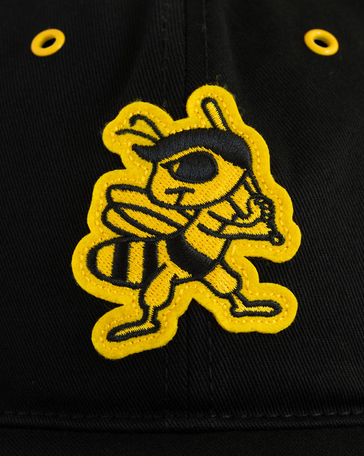 Close-up of the EFF Salt Lake City Bees Cotton Twill Ballcap in black, featuring a yellow and black embroidered cartoon hornet with a bat and two yellow ventilation holes above the mascot.