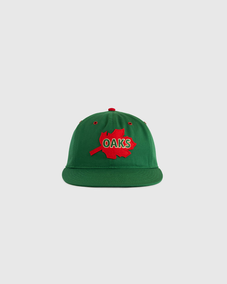 The EFF Oakland Oaks Cotton Twill Ballcap is a green hat featuring a red maple leaf patch and bold red and white OAKS lettering, shown against a plain light gray background.