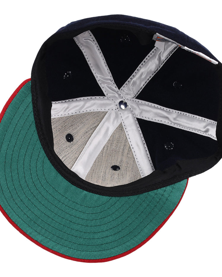 A close-up of the EFF Oklahoma City Indians 1948 Vintage Ballcap reveals a green underbrim, red edge, black interior, and silver stitched strips forming an X—a detailed look inside this classic wool cap.