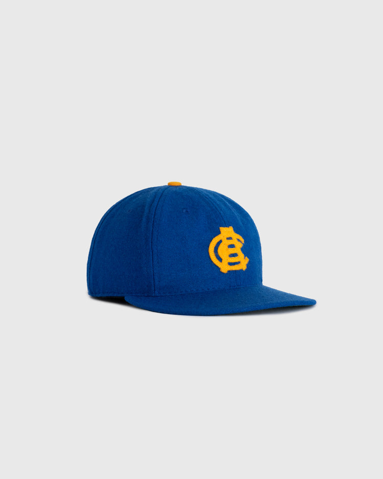 The EFF Chinese Athletic Club (Hawaii) 1910 Authentic Wool Ballcap is a royal blue flat-brim cap with a yellow embroidered interlocking LC logo, paying tribute to Hawaii baseball history and shown on a light gray background.