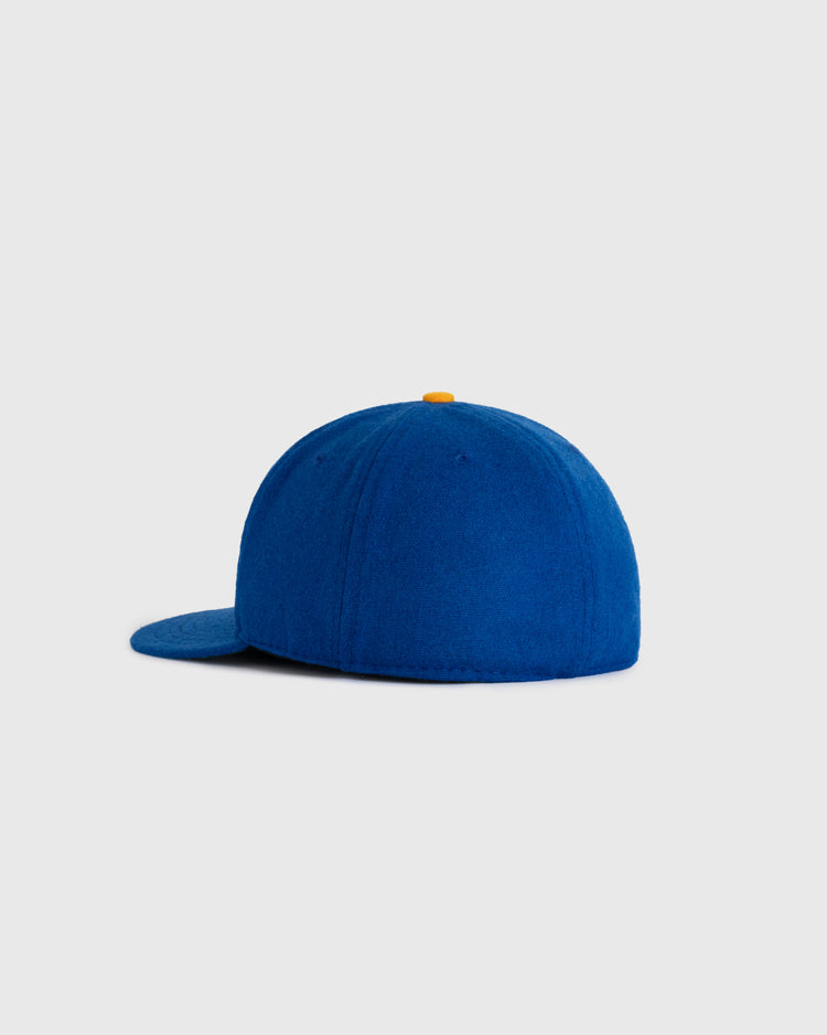 The EFF Chinese Athletic Club (Hawaii) 1910 Authentic Wool Ballcap, shown from the back in royal blue with a flat brim and yellow top button, is set against a plain light gray background.