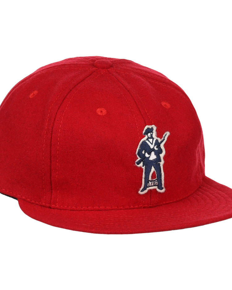 The EFF Greensboro Patriots 1922 Vintage Ballcap is a bright red hat with an embroidered figure in a suit holding a guitar on the front left side.