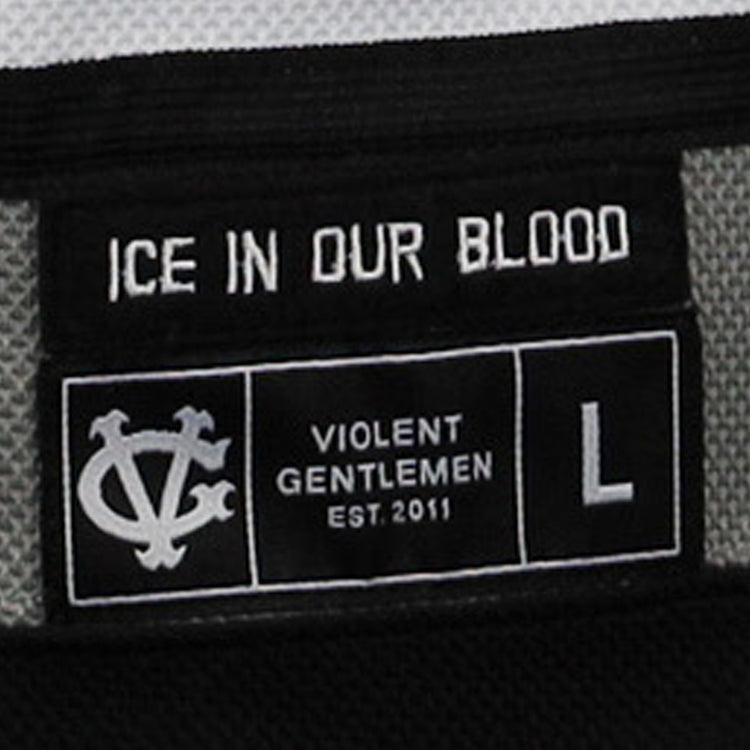 Close-up of a black clothing label on the Violent Gentlemen x EFF Collection Hockey Jersey by EFF, reading ICE IN OUR BLOOD and VIOLENT GENTLEMEN EST.2011, with a white symbol and size L shown.