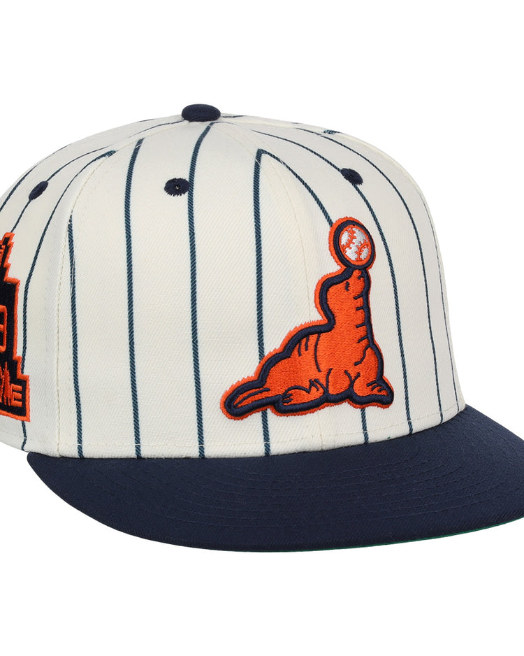 The EFF San Francisco Seals Pinstripe Fitted Ballcap features a white body with navy pinstripes, a navy brim, an orange embroidered seal with a black baseball on its nose, and an orange/navy Seals patch on the side.