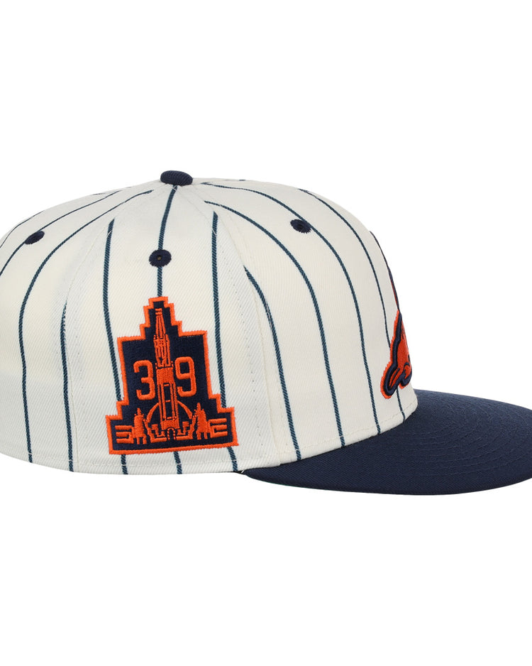The EFF San Francisco Seals Pinstripe Fitted Ballcap features white fabric with thin navy pinstripes, a navy brim, and an orange patch showing 39 and a city skyline—honoring the Seals legacy.