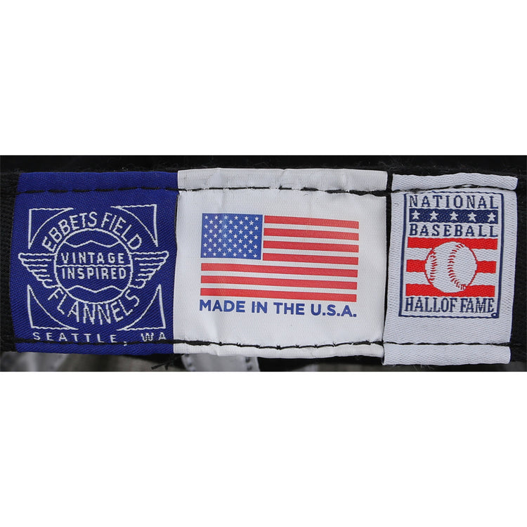 Three fabric labels—Ebbets Field Flannels Vintage Inspired Seattle, WA, an American flag with Made in the U.S.A., and National Baseball Hall of Fame with a baseball—adorn the Frank Thomas Signature Series Ballcap - Navy.