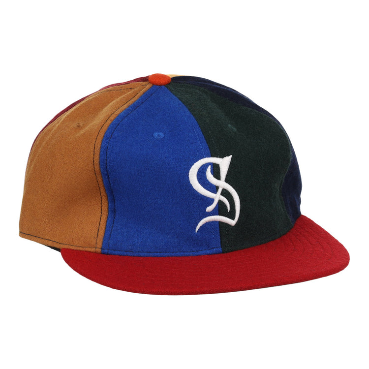 The EFF Santurce Cangrejeros Vintage Inspired Pinwheel Ballcap features brown, blue, green, and navy panels, a red brim, an orange top button, and a white stylized S logo on the front.