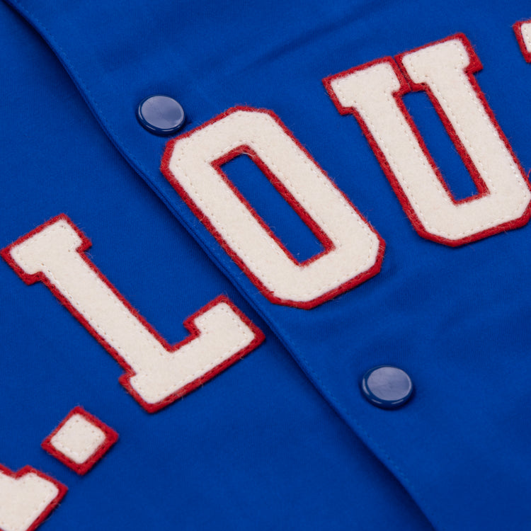 Close-up of the EFF St. Louis Stars Satin Windbreaker shows blue fabric with raised white letters outlined in red, spelling L.O.U., and blue snap buttons—capturing vintage Negro National League style.