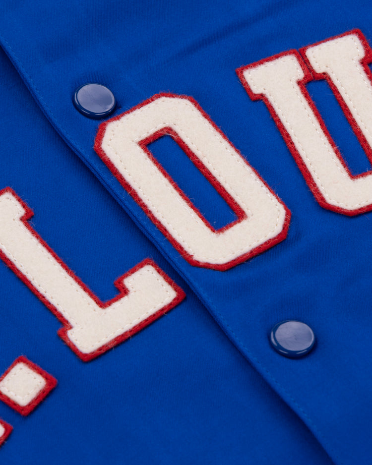 Close-up of the EFF St. Louis Stars Satin Windbreaker shows blue fabric with raised white letters outlined in red, spelling L.O.U., and blue snap buttons—capturing vintage Negro National League style.