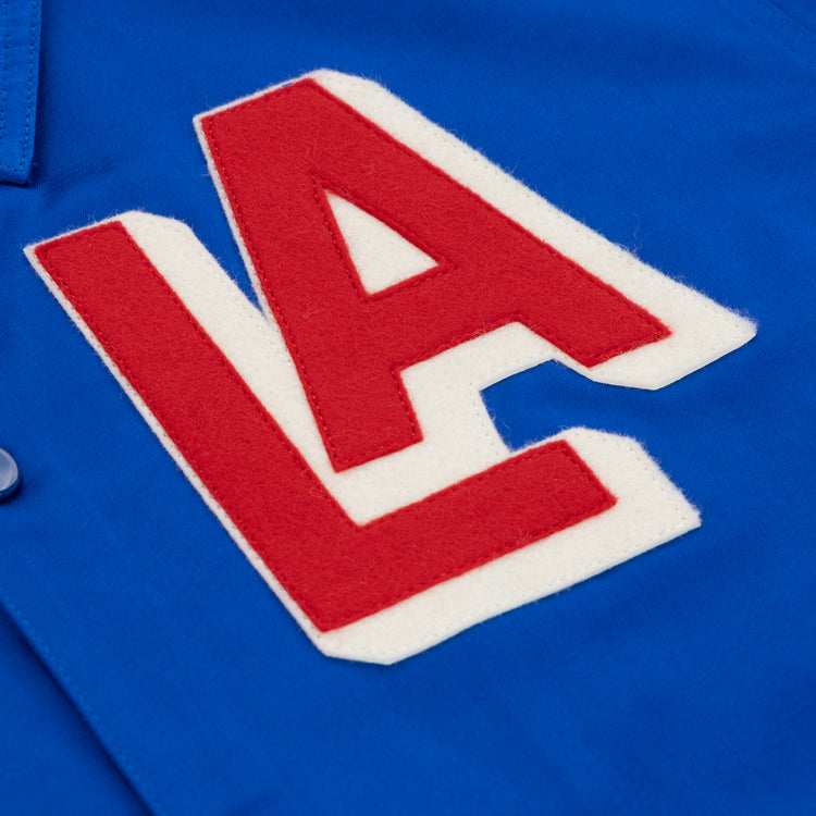A close-up of blue fabric from the EFF Los Angeles (PCL) Satin Windbreaker featuring large red and white varsity LA letters, capturing vintage style and Pacific Coast League nostalgia.