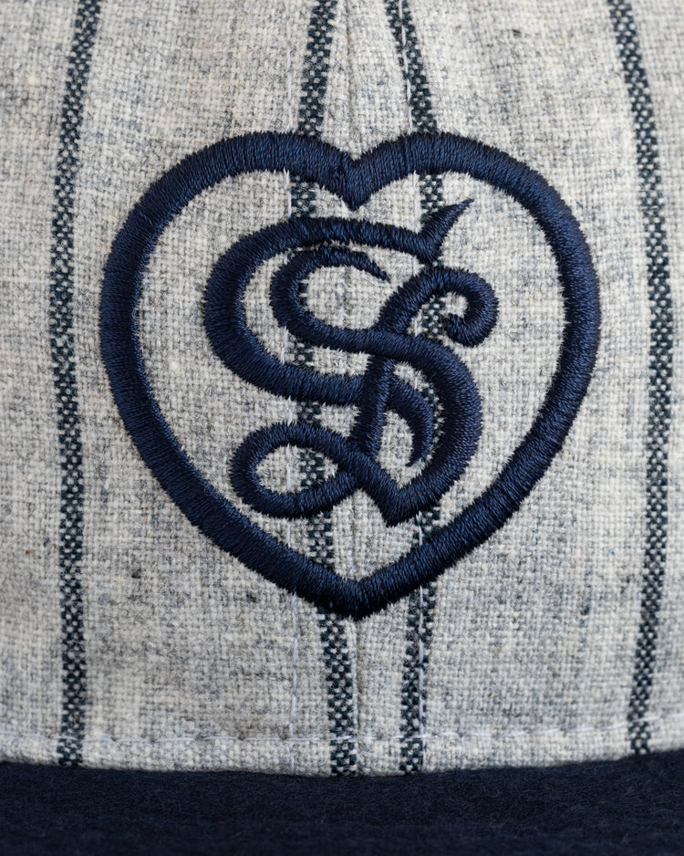 Close-up of the EFF Sacramento Senators Authentic Wool Ballcap—a gray vintage cap with dark vertical stripes and a navy blue embroidered heart outline featuring overlapping S and L letters.
