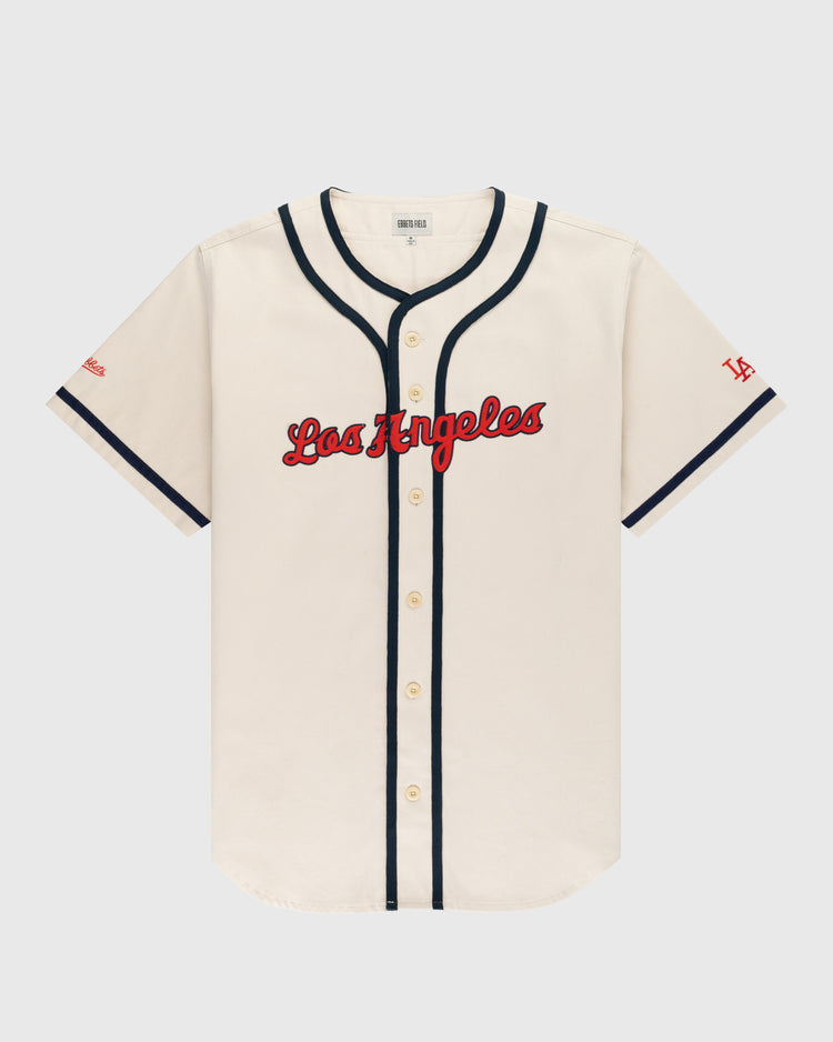 The Ebbets Field Los Angeles Angels (PCL) Cotton Twill Jersey features a cream body, red Los Angeles script, navy trim on buttons and sleeves, and red LA on the left sleeve—ideal for any Pacific Coast League fan.