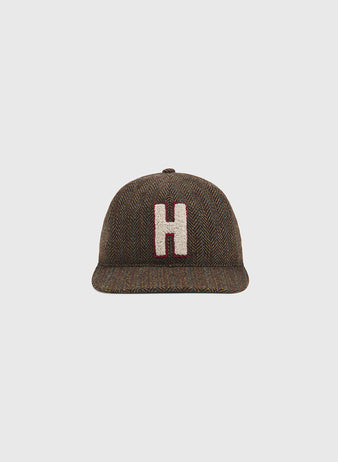 The Ebbets Field Harvard University Herringbone Ballcap features a brown herringbone pattern and a prominent white and red “H” on the front, shown against a plain light gray background.
