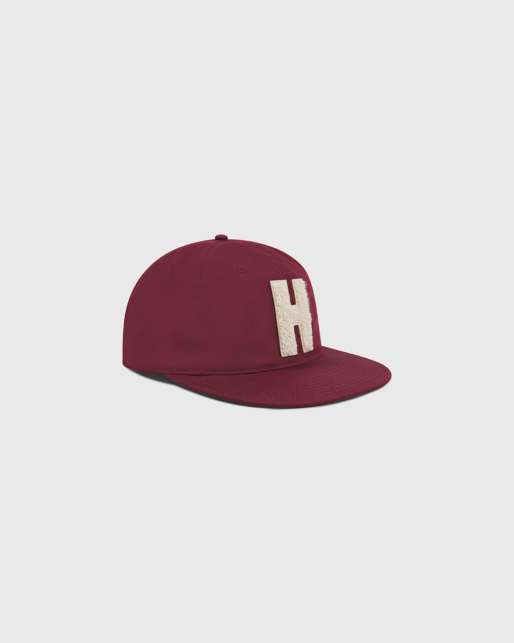 The Ebbets Field Harvard University Chenille H Cotton Twill Ballcap, featuring a maroon color and a prominent white letter H on the front, is displayed against a plain light gray background.