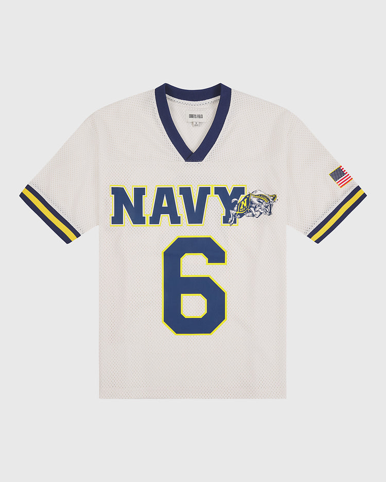 The US Naval Academy Mesh Football Jersey by Ebbets Field showcases classic white mesh fabric adorned with bold blue and yellow “NAVY” lettering, a striking bulldog mascot, number 6, and retro blue and yellow stripes on the sleeves. An American flag patch on the right sleeve enhances its authentic appeal, making this Ebbets Field Navy football jersey a must-have for any fan or collector.