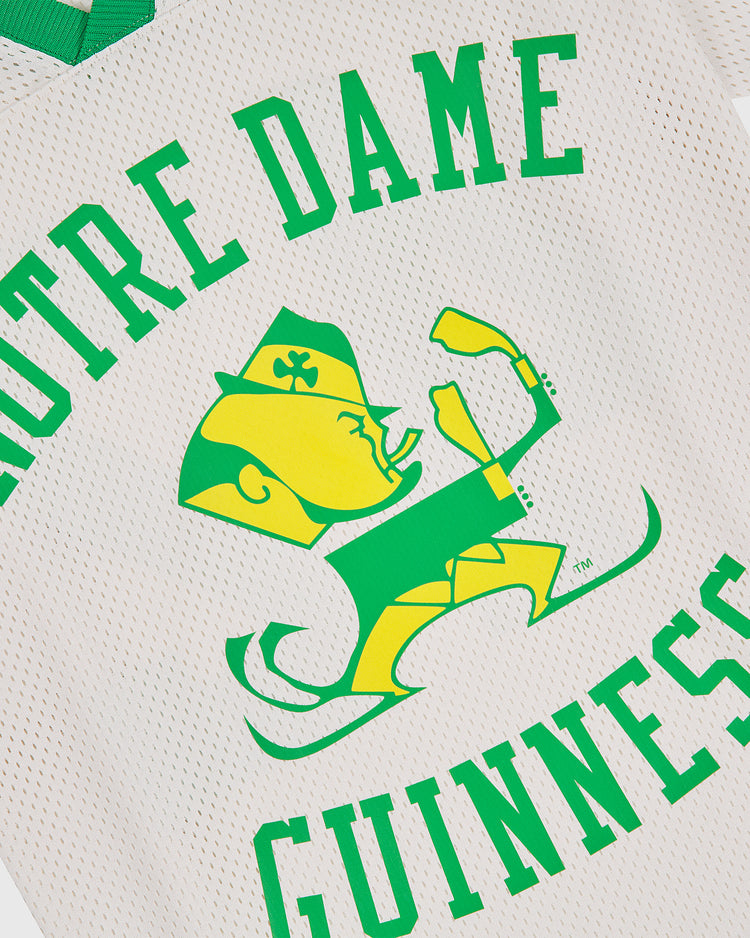 Show your Irish pride with the Notre Dame X Guinness Mesh Football Jersey from Ebbets Field. This vintage-inspired jersey features white mesh fabric adorned with a bold green and yellow graphic of a leprechaun in a fighting stance, framed by green “Notre Dame Guinness” text for classic charm. Celebrate your heritage in style with this standout piece from Ebbets Field.