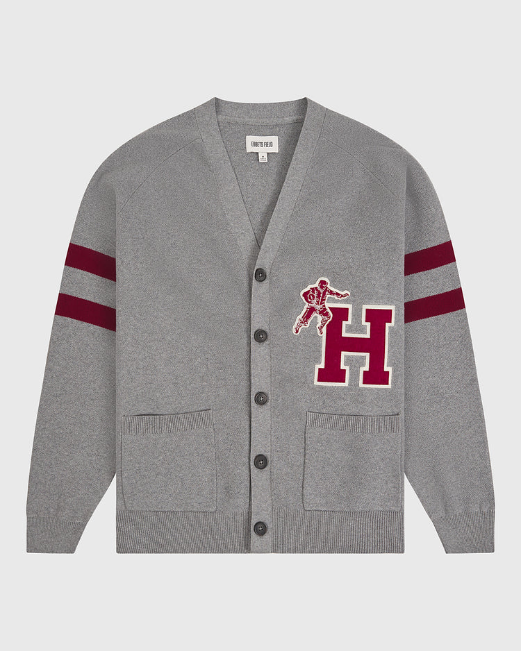 The Ebbets Field Harvard University Cotton Varsity Cardigan features a gray design with two front pockets, black buttons, maroon double stripes on the sleeves, and a large maroon “H” patch adorned with a football player graphic on the left chest.