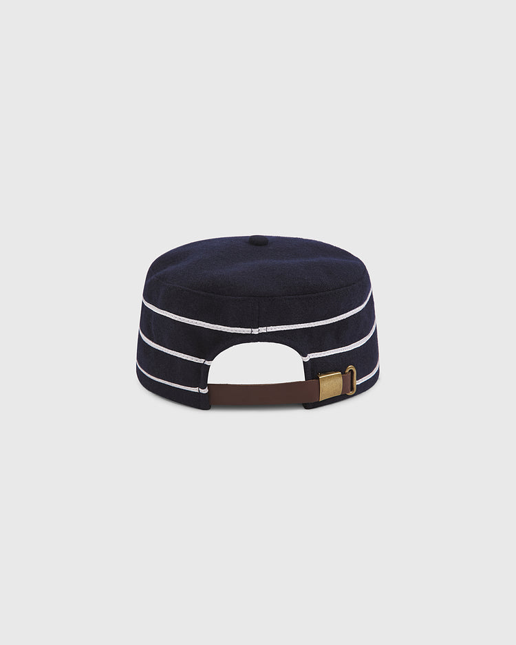 The Notre Dame Pillbox Wool Ballcap by Ebbets Field features a navy blue design with two white horizontal stripes, seen from the back with an adjustable brown strap and brass buckle—an iconic nod to classic collegiate style inspired by vintage caps worn by Fighting Irish fans.