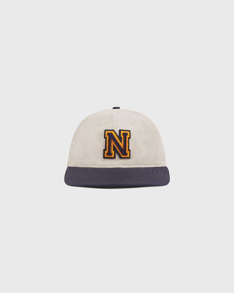 The Ebbets Field Navy 1958 Logo Cotton Twill Ballcap features a beige crown with a navy blue brim and a large, yellow-outlined letter N embroidered on the front, displayed centered against a plain white background.