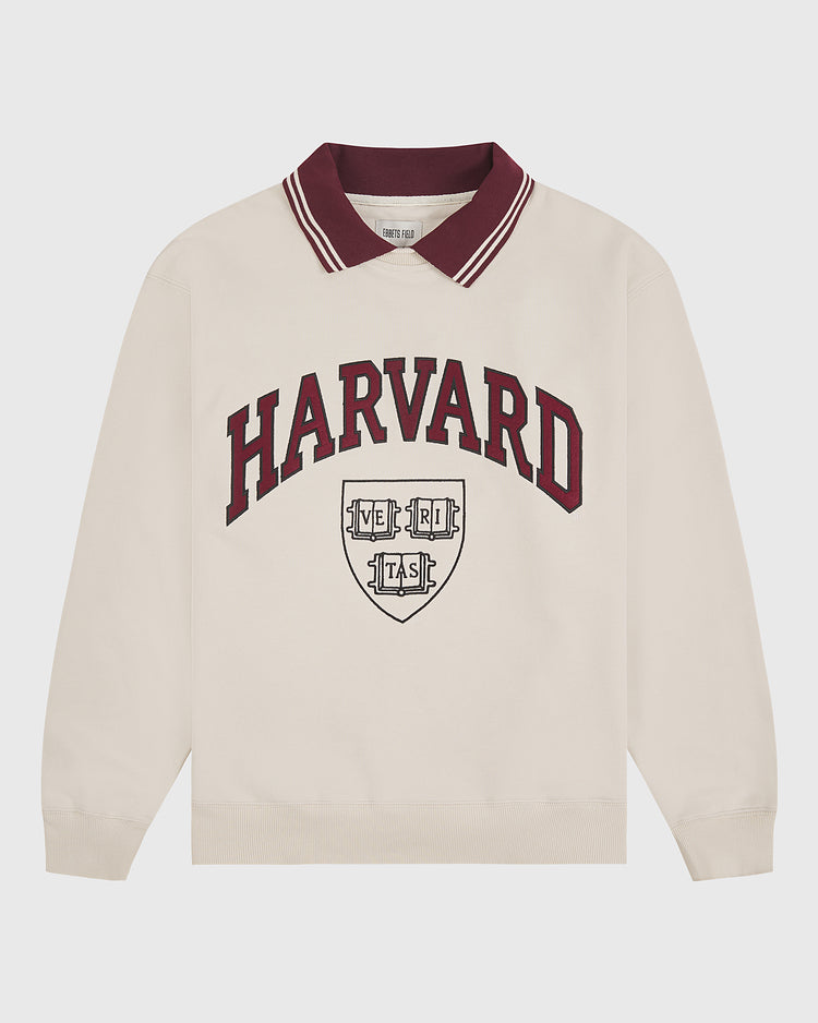 Ebbets Field’s Harvard University Collared Crewneck Sweatshirt is a beige long-sleeve top featuring a maroon collar with two thin white stripes and “HARVARD” in maroon text above the university shield printed in maroon and black.