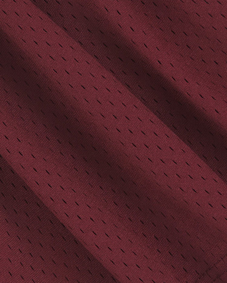 Close-up of the maroon athletic mesh fabric from the Ebbets Field Texas A&M Mesh Football Jersey, featuring small, evenly spaced holes and diagonal folds that highlight its vintage texture and pattern, reminiscent of classic Aggies football team jerseys.