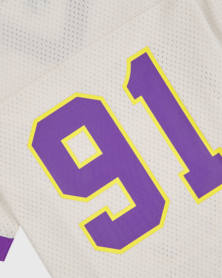Close-up of an Ebbets Field University of Washington Mesh Football Jersey featuring large purple number 91 outlined in yellow on white mesh fabric, with a glimpse of purple cuffed sleeve—a classic design inspired by the Huskies’ Rose Bowl era.