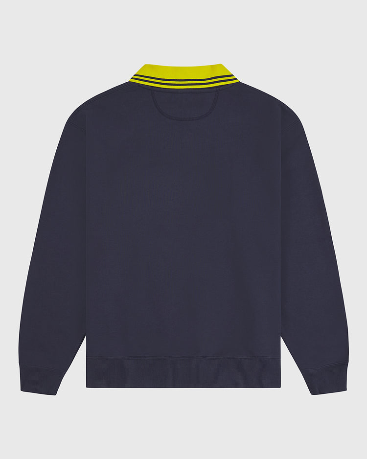 The Ebbets Field University of Michigan Collared Crewneck is pictured from the back, showcasing its navy blue long sleeves and distinctive yellow collar with two dark blue stripes, set against a plain white background.