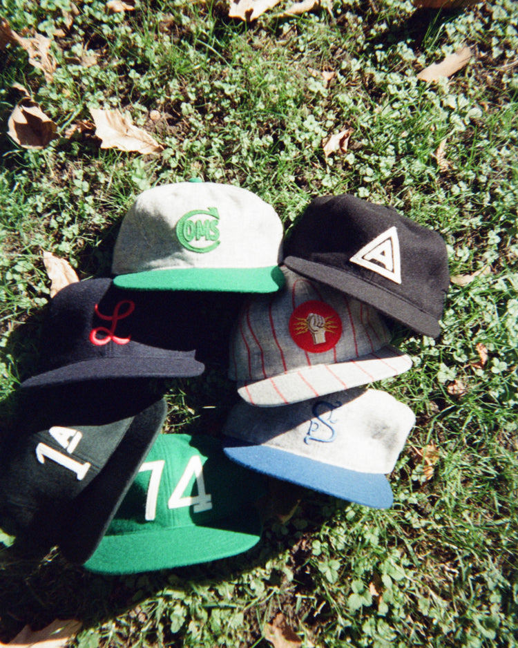 Six Ebbets Field Mystery Caps of Mexico – Agrario de México 1935 Wool Ballcaps arranged in a circle on grass, featuring various colors, brims, and embroidered emblems.