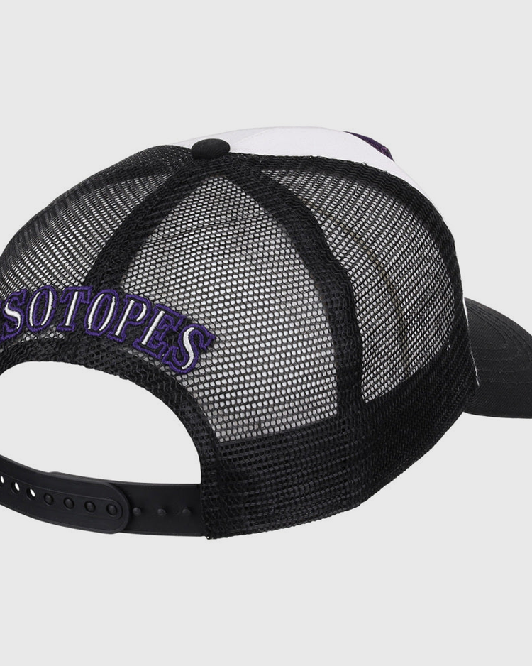 The Ebbets Field Albuquerque Isotopes MiLB Trucker Ballcap features black mesh, white front panels, and “ISOTOPES” embroidered in purple and white above the back opening.