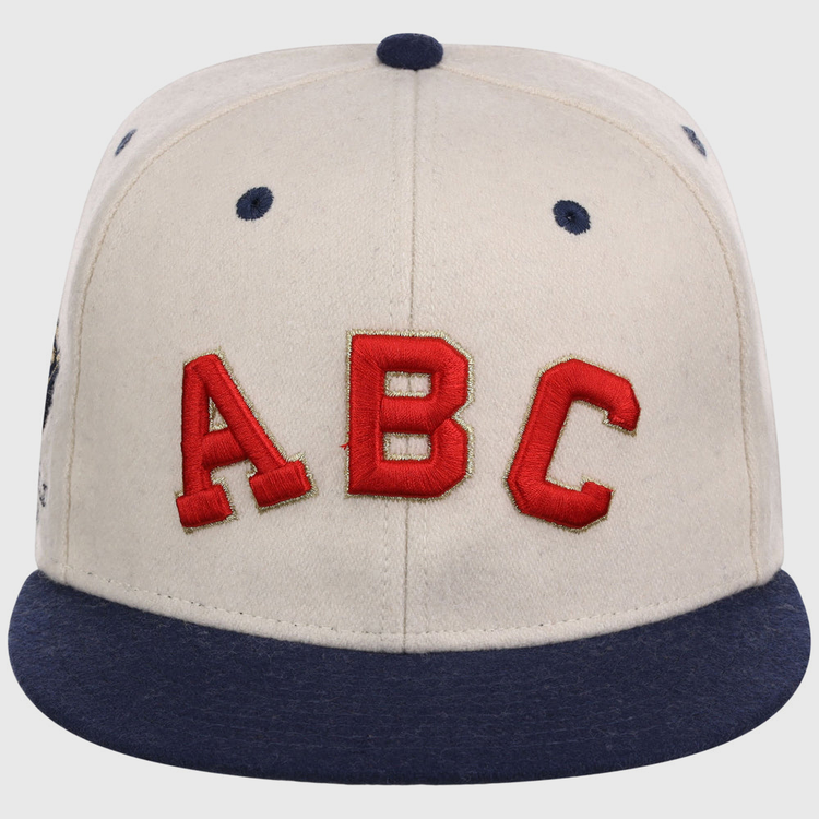 The Atlanta Black Crackers NLB Ballpark Fitted Ballcap by Ebbets Field is a beige cap with a dark blue brim, button, and eyelets, featuring large red 