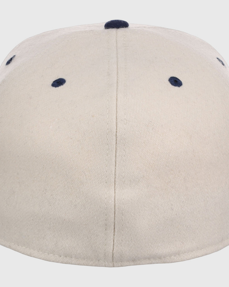 The Ebbets Field Atlanta Black Crackers NLB Ballpark Fitted Ballcap is beige, shown from the back with a central seam and four navy blue ventilation holes near the top.