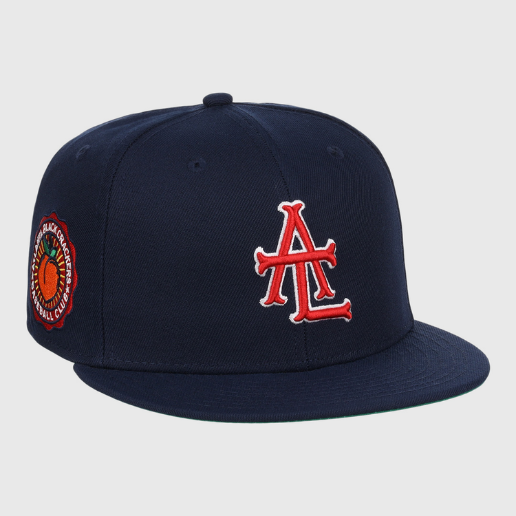 The EFF Atlanta Black Crackers NLB Team Color Fitted Ballcap is a vintage-inspired navy hat featuring a bold red and white logo on the front and an orange-and-black round patch on the side.