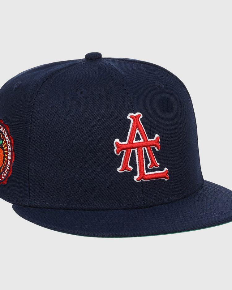 The EFF Atlanta Black Crackers NLB Team Color Fitted Ballcap is a vintage-inspired navy hat featuring a bold red and white logo on the front and an orange-and-black round patch on the side.