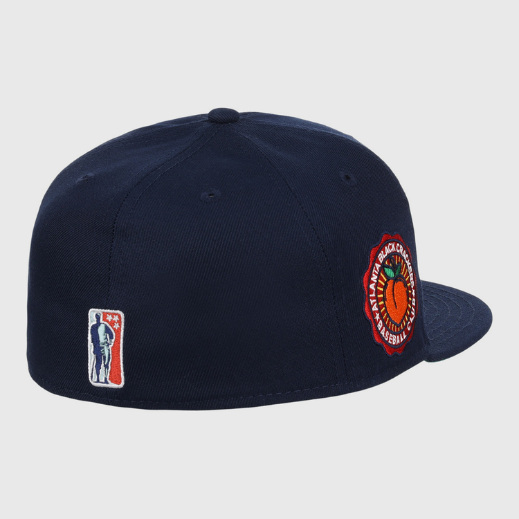 The EFF Atlanta Black Crackers NLB Team Color Fitted Ballcap is a vintage-inspired navy hat with a round orange and green side patch and a small man-with-bat embroidered logo on the back.