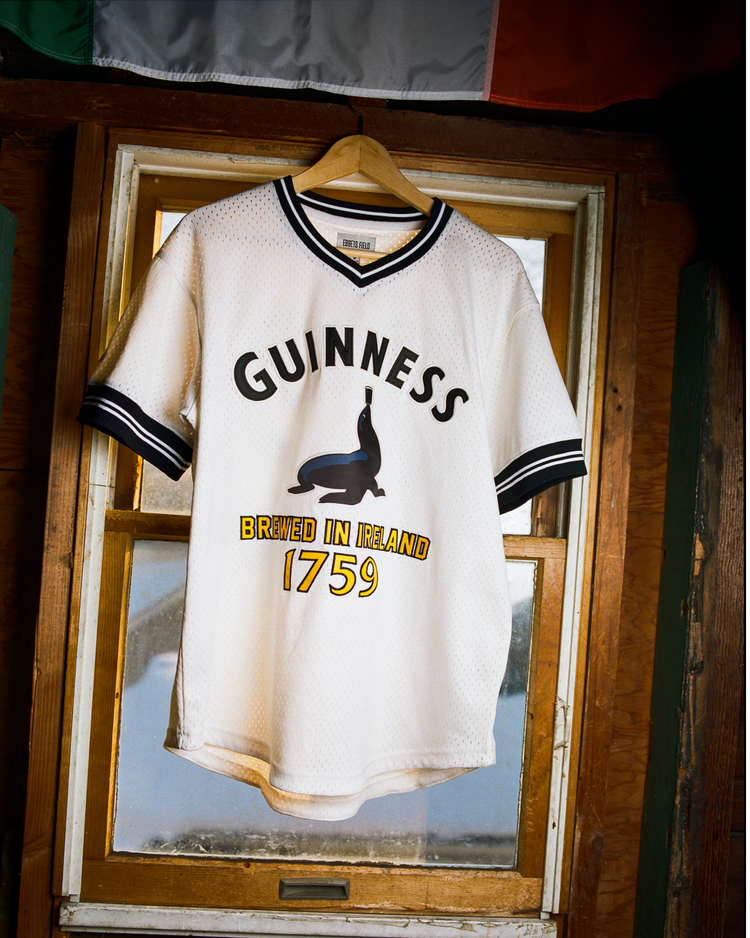 The Ebbets Field Guinness Seal Mesh V-Neck Jersey features white mesh, black trim, a seal graphic, and 