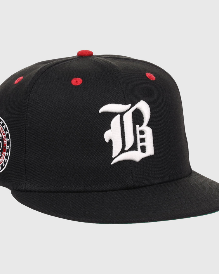 The EFF Birmingham Black Barons NLB Flip Fitted Ballcap is a black cap with a white gothic B, red top button and eyelets, plus a circular patch honoring the Negro National League and Birmingham Black Barons, featuring 1920.