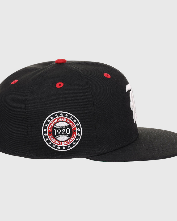 The EFF Birmingham Black Barons NLB Flip Fitted Ballcap is a black hat with a flat brim, red top button, red stitched air holes, and a circular Birmingham Black Barons 1920 patch honoring the Negro National League.