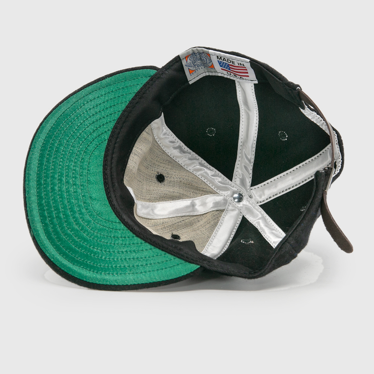 The image shows the inside of an EFF Bisbee-Douglas Copper Kings 1951 Vintage Ballcap, featuring a green undervisor, white fabric strips, and a Made in USA tag sewn into the inner band.