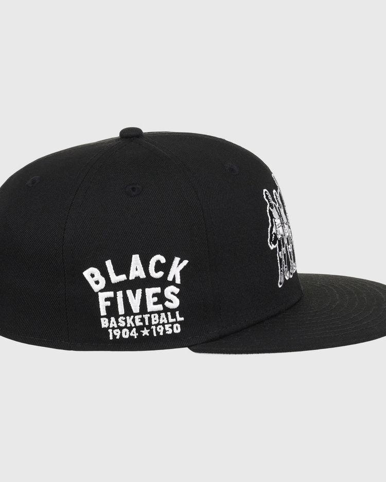 The Black Fives Fitted Ballcap by Ebbets Field Flannels is a black cap with white BLACK FIVES BASKETBALL 1904-1950 embroidery on the side and a small image of Black basketball players on the front.